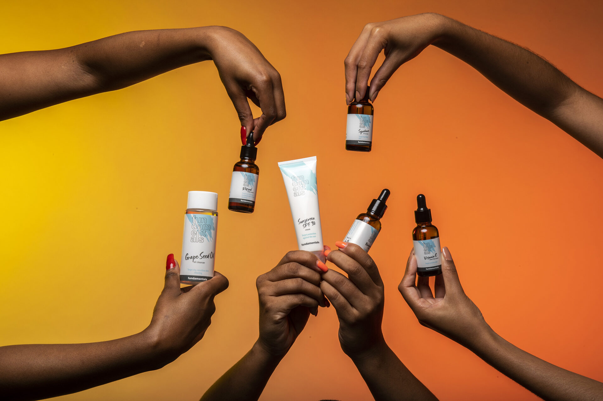 women's hands holding skincare products by fundamentals