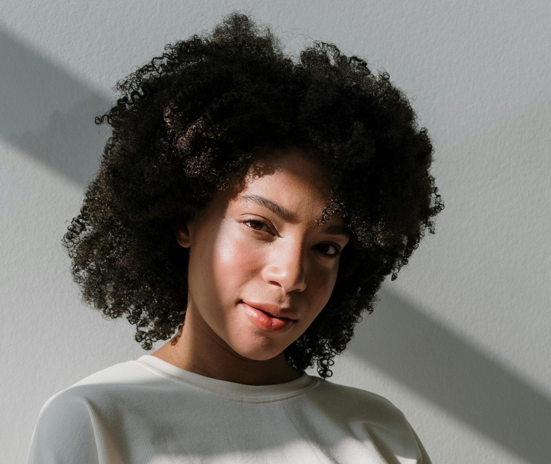 Person with curly hair, neutral background during spring