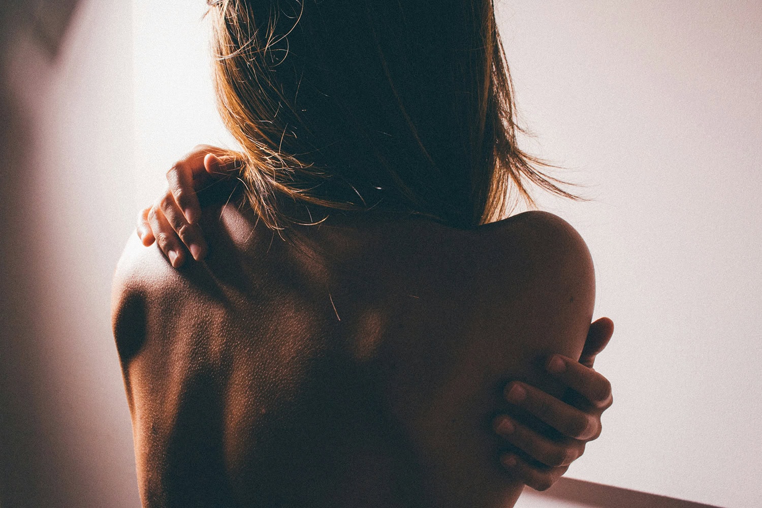 Woman embracing herself, back view of her atopic eczema