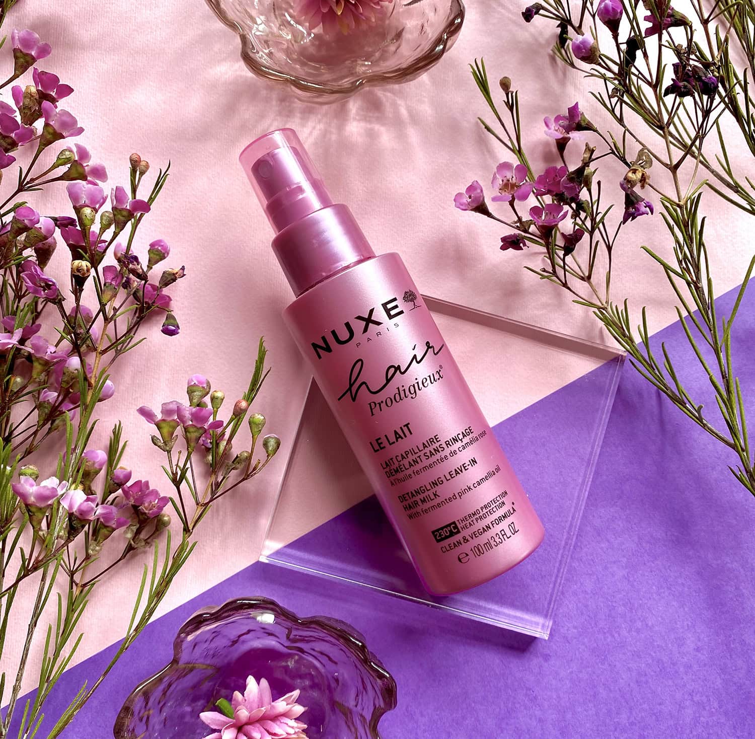 Nuxe Hair Prodigieux Pink hair product surrounded by flowers