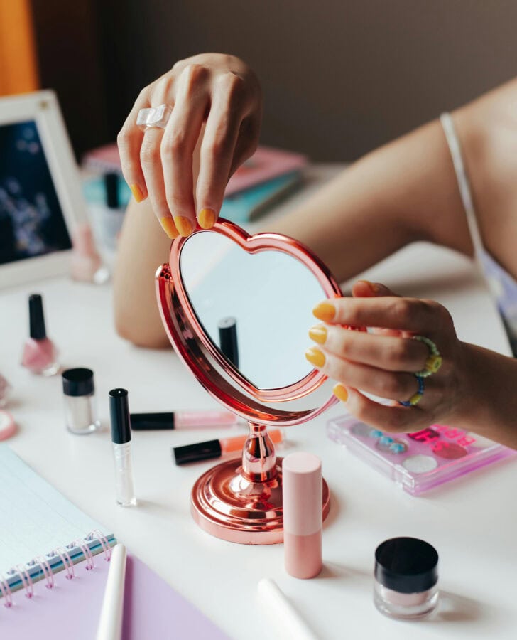 woman looking at beauty products on her dressing table