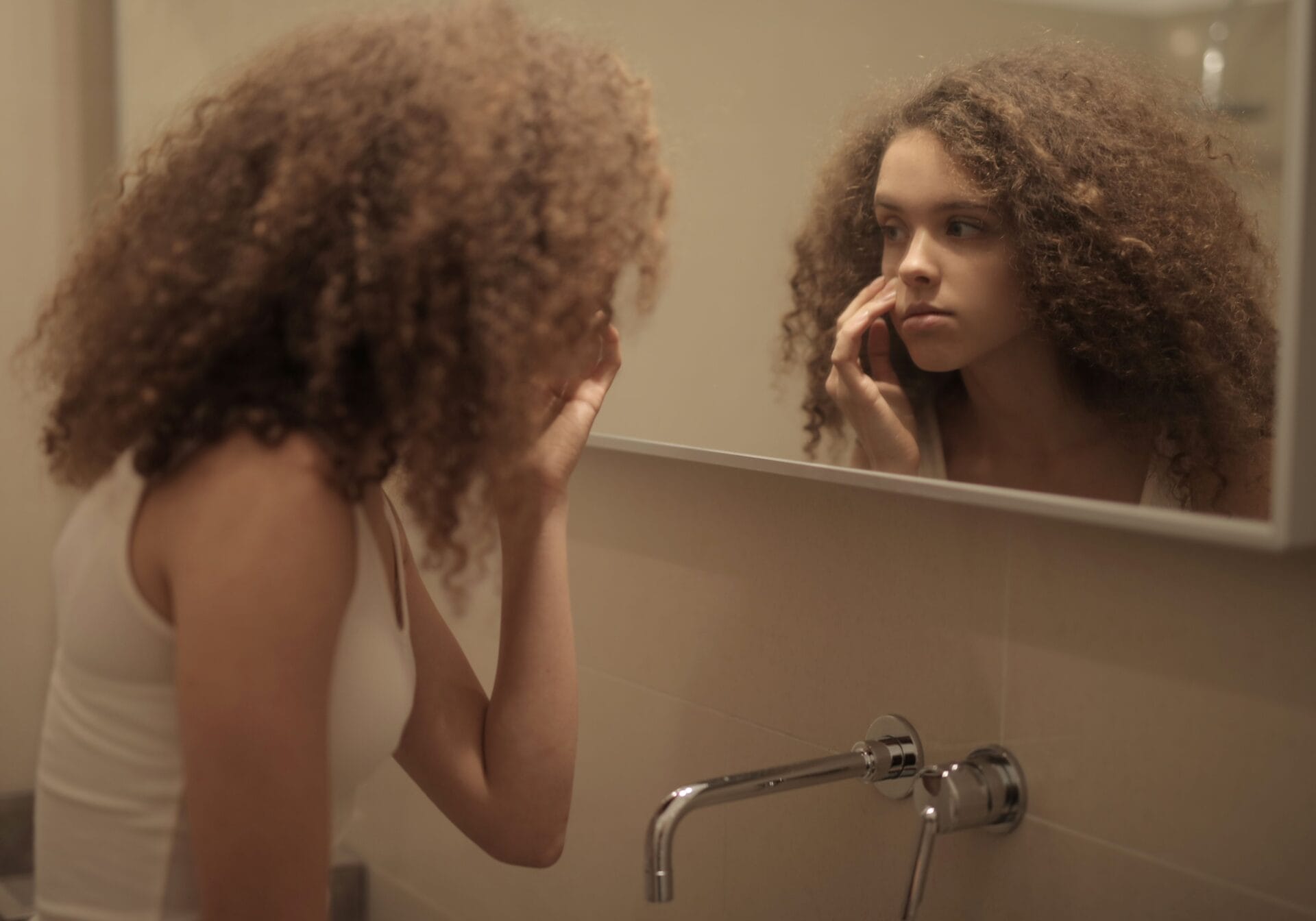 young girl with cosmeticorexia looking in the mirror
